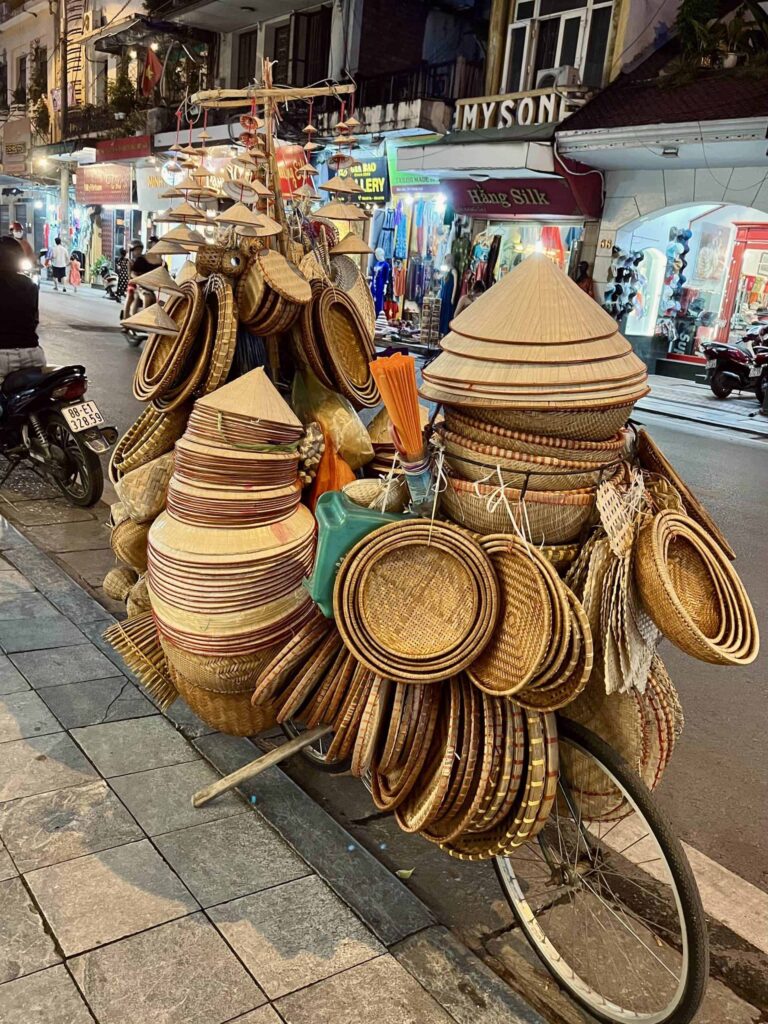 A street vendor selling traditional rice hats in Hanoi's Old Quarter.