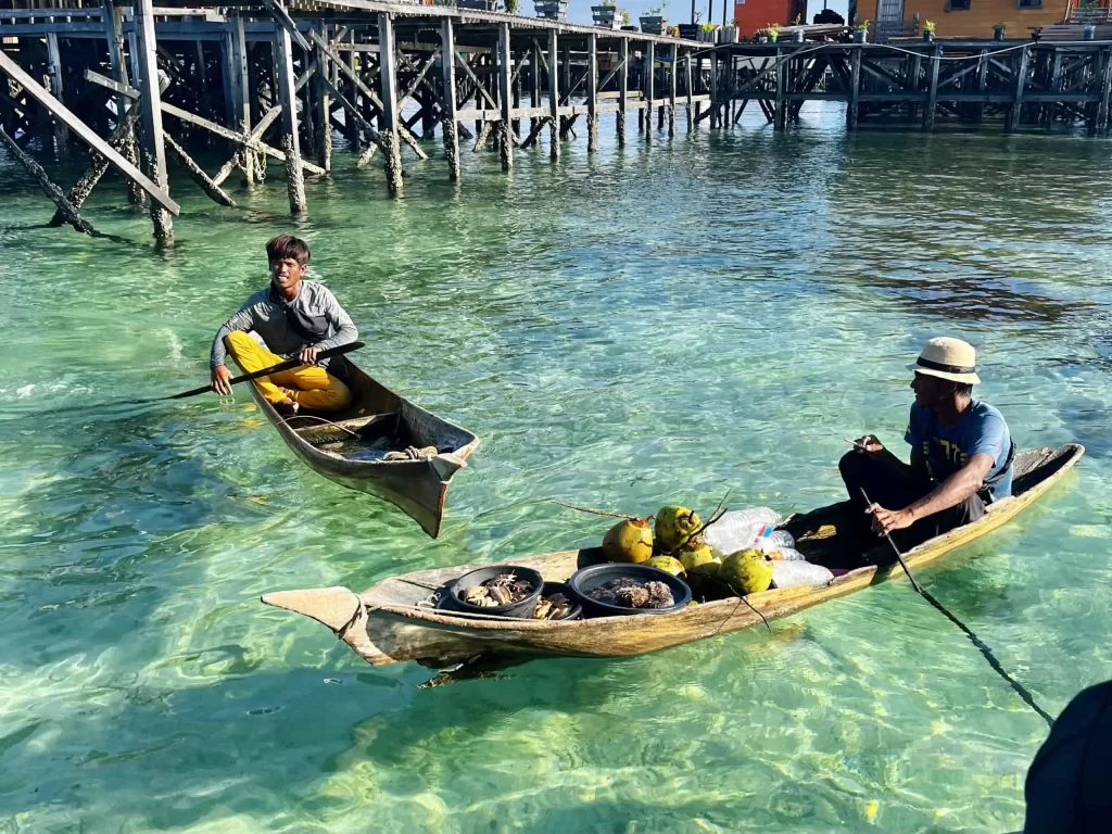 Visiting Semporna: What to Know Before You Dive or Transit 5 Two Bajau-Laut in their small boats in Semporna, offering goods for sale.