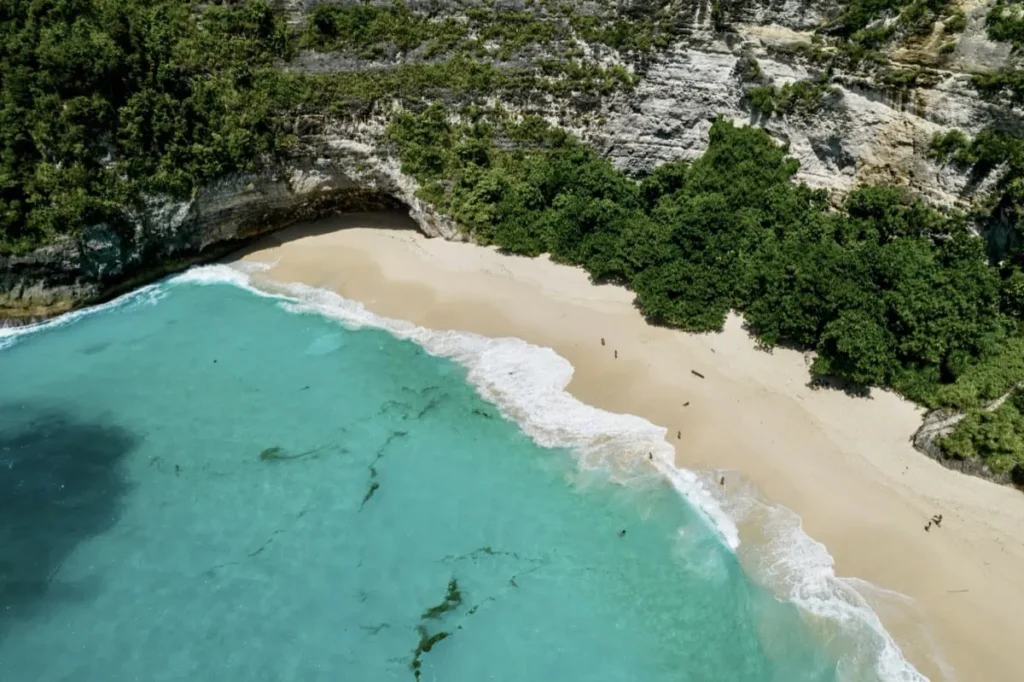 Aerial shot of Nusa Penida’s curved shoreline and limestone cliffs.