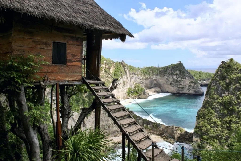 Wooden treehouse on a cliff overlooking turquoise waters and rugged coastline, a scenic photo spot among the best things to do in Nusa Penida.