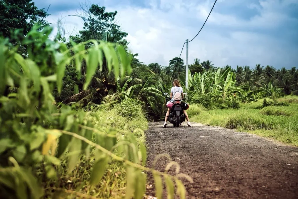 Woman riding a scooter through lush jungle roads on Nusa Penida, showcasing the island’s wild beauty and adventurous spirit.