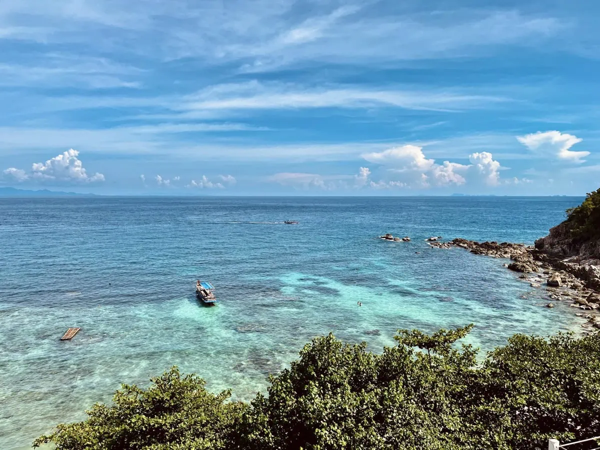 Scenic view over Sai Daeng Bay with turquoise water, boats, and a rocky shoreline.