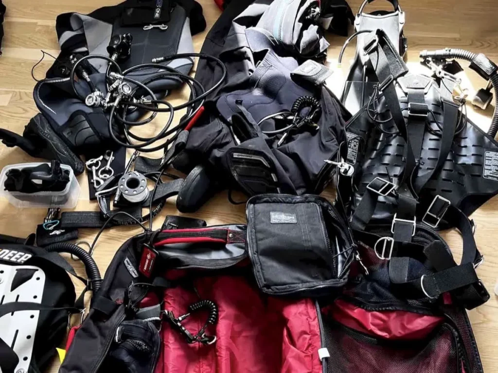 Scuba diving gear laid out on the floor including wetsuit BCD regulator mask fins and accessories being organized while packing for a dive trip to Sipadan.